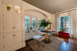 Dining room with crown molding, dark wood-type flooring, a healthy amount of sunlight, and french doors