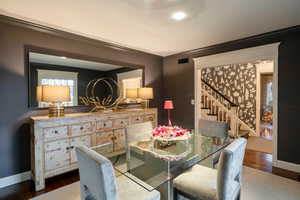 Dining room with crown molding and dark wood-type flooring