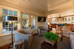 Living room featuring ornate columns, ornamental molding, wood-type flooring, and french doors