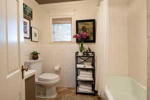 Bathroom with hardwood / wood-style flooring, tile walls, and shower / bathtub combination with curtain