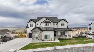 View of front of house with a mountain view, a porch, a garage, and a front yard