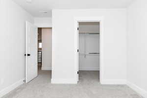 Unfurnished bedroom featuring light carpet and a closet