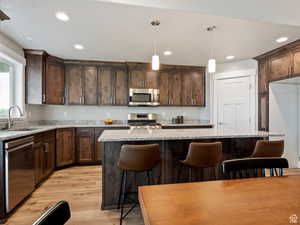 Kitchen featuring sink, a center island, stainless steel appliances, pendant lighting, and light wood-type flooring