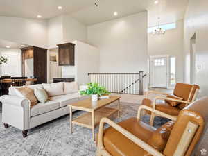 Living room with light carpet, an inviting chandelier, and high vaulted ceiling