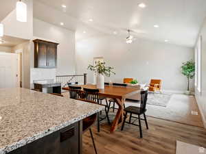 Dining space featuring high vaulted ceiling, ceiling fan, and dark wood-type flooring