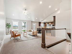 Living room featuring light carpet, high vaulted ceiling, and ceiling fan