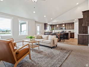 Living room featuring light wood-type flooring, high vaulted ceiling, ceiling fan, and sink