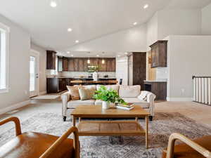 Living room featuring light colored carpet, sink, and high vaulted ceiling