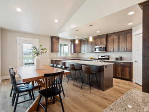 Dining room with plenty of natural light, light hardwood / wood-style floors, lofted ceiling, and sink