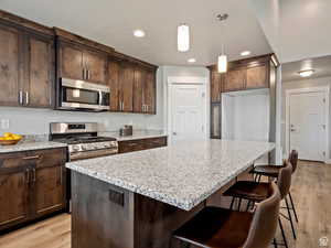 Kitchen featuring light hardwood / wood-style floors, light stone countertops, and stainless steel appliances