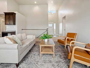 Carpeted living room with a towering ceiling and an inviting chandelier