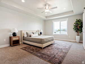 Bedroom featuring carpet floors, a tray ceiling, and ceiling fan