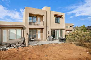 Rear view of property featuring a fire pit, a patio area, and a balcony