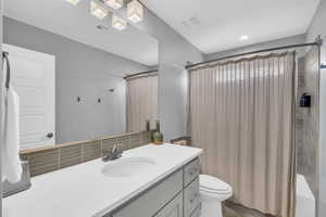 Full bathroom featuring backsplash, shower / tub combo with curtain, vanity, and toilet