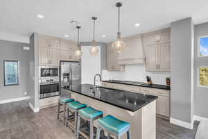 Kitchen featuring sink, dark wood-type flooring, stainless steel appliances, a breakfast bar, and a center island with sink