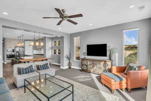 Carpeted living room with ceiling fan and sink