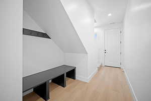 Corridor featuring light wood-type flooring and lofted ceiling