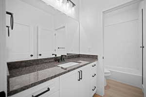 Full bathroom with vanity, hardwood / wood-style flooring, toilet, and shower / washtub combination