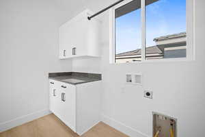 Clothes washing area featuring cabinets, hookup for a washing machine, light hardwood / wood-style flooring, and electric dryer hookup