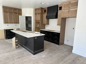 Kitchen featuring a center island, a textured ceiling, light hardwood / wood-style flooring, custom exhaust hood, and black electric stovetop