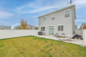 Back of house featuring a lawn and a patio