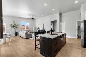Kitchen with stainless steel appliances, a sink, a ceiling fan, a kitchen breakfast bar, and light countertops
