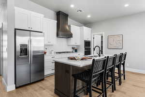 Kitchen featuring appliances with stainless steel finishes, custom range hood, a sink, light countertops, and white cabinetry