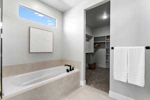 Full bath featuring a bath, a spacious closet, and tile patterned floors