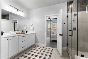 Ensuite bathroom featuring double vanity, a shower stall, tile patterned floors, baseboards, and ceiling fan