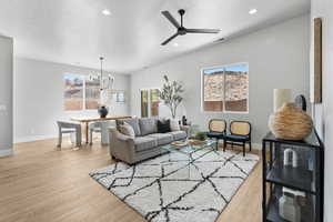 Living room with recessed lighting, light wood-style flooring, a chandelier, a ceiling fan, and baseboards