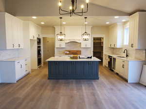 Kitchen with sink, pendant lighting, hardwood / wood-style floors, a center island, and white cabinetry