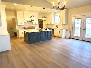 Kitchen featuring pendant lighting, a center island, white cabinetry, and french doors