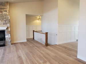 Unfurnished living room with lofted ceiling, light wood-type flooring, and a fireplace