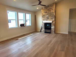 Unfurnished living room with ceiling fan, a fireplace, vaulted ceiling, and hardwood / wood-style flooring