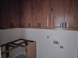 Clothes washing area featuring cabinets, hookup for a washing machine, and electric dryer hookup