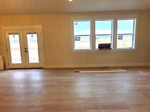 Unfurnished room with light wood-type flooring, radiator, and french doors