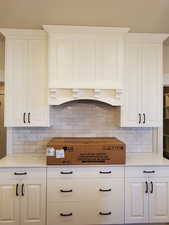 Kitchen with decorative backsplash and white cabinetry