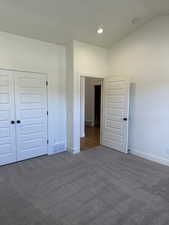 Unfurnished bedroom with a closet, carpet, and vaulted ceiling