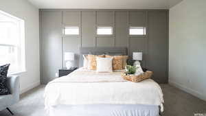 Bedroom featuring light carpet and multiple windows