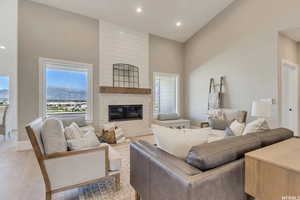 Living room with a brick fireplace, high vaulted ceiling, and light wood-type flooring