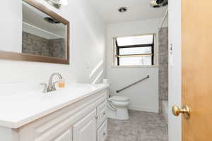 Full bathroom with tile patterned floors, tiled shower / bath, vanity, and toilet