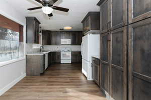 Kitchen featuring white appliances, sink, ceiling fan, light stone countertops, and light hardwood / wood-style floors