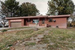 Ranch-style house with a garage, a front lawn, and a wall unit AC