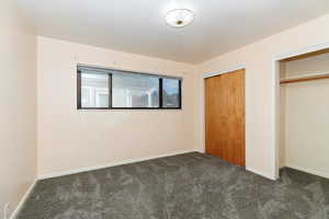 Unfurnished bedroom with dark carpet