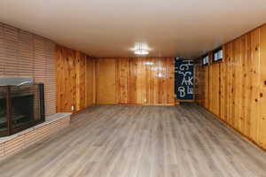 Basement with hardwood / wood-style floors, wood walls, and a brick fireplace