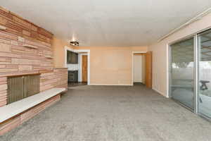 Unfurnished living room with carpet flooring, a textured ceiling, and a fireplace