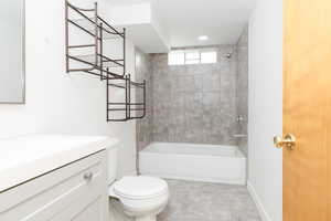 Full bathroom with tile patterned floors, vanity, tiled shower / bath, and toilet