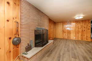 Unfurnished living room with a fireplace, hardwood / wood-style flooring, and wooden walls