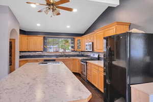 Kitchen with decorative backsplash, appliances with stainless steel finishes, dark hardwood / wood-style flooring, sink, and vaulted ceiling with beams