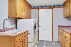 Laundry area with cabinets, washer and clothes dryer, and sink